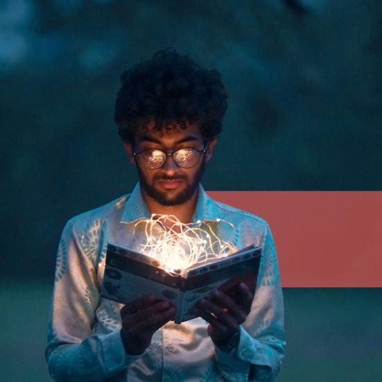 En ung mand læser i en lysende bog