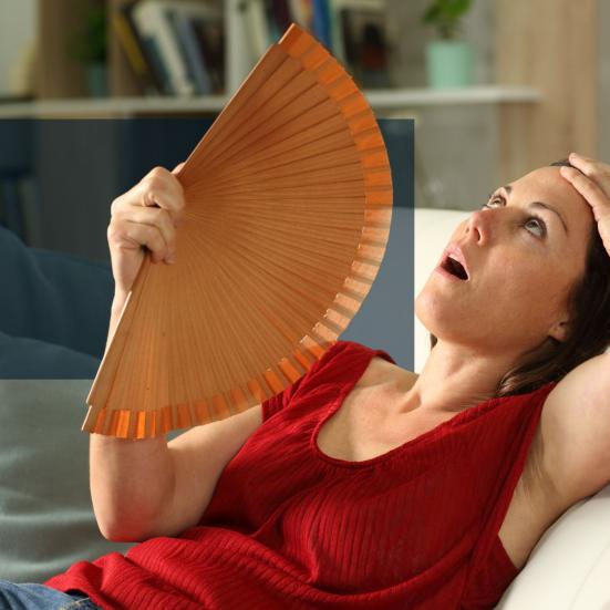 Kvinde som har det varmt og køle sig ned med en vifte