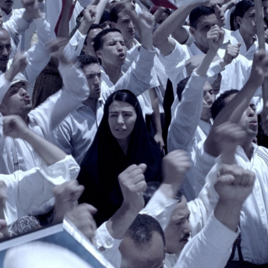 kvinde med tørklæde i sort til demonstration med en masse mænd i hvidt