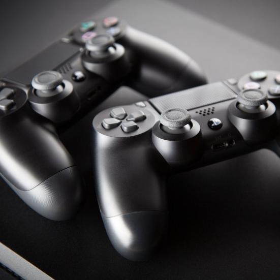 To sorte playstation-controllere på et sort bord