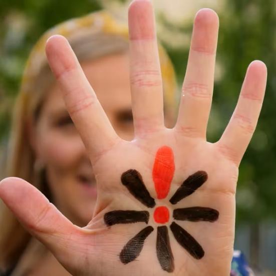 Kvindehånd med påmalet Knæk Cancer-blomst 