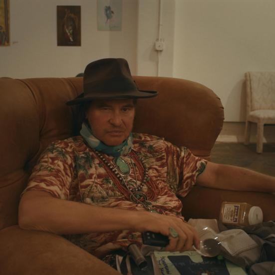 val kilmer sidder i en stol og ser på os