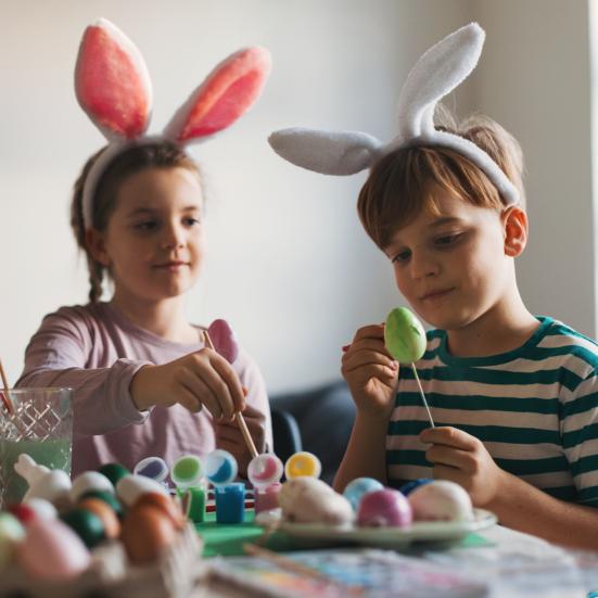 2 børn med kaninører maler påskeæg