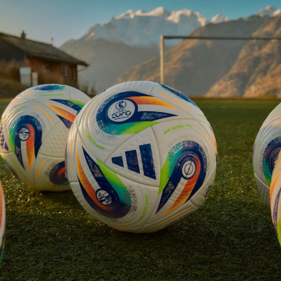 Closeup af fodbolde på fodboldbane med bjerglandskab i baggrunden