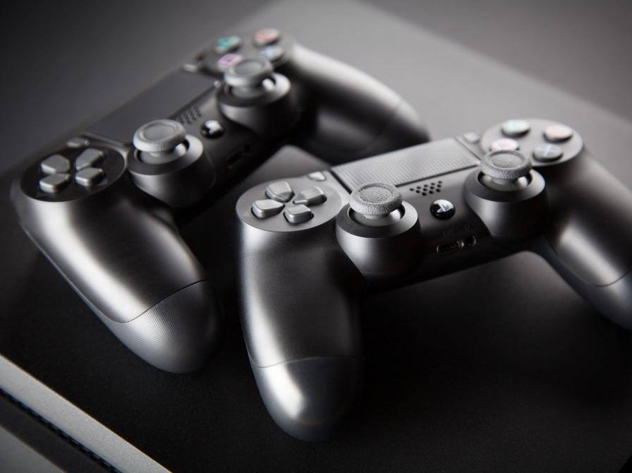 To sorte playstation-controllere på et sort bord