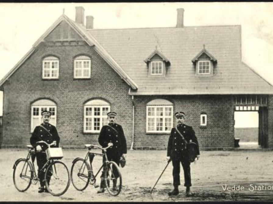 foto af foto af tre landpostbude med cykler og stok foran Vedde Station 1907