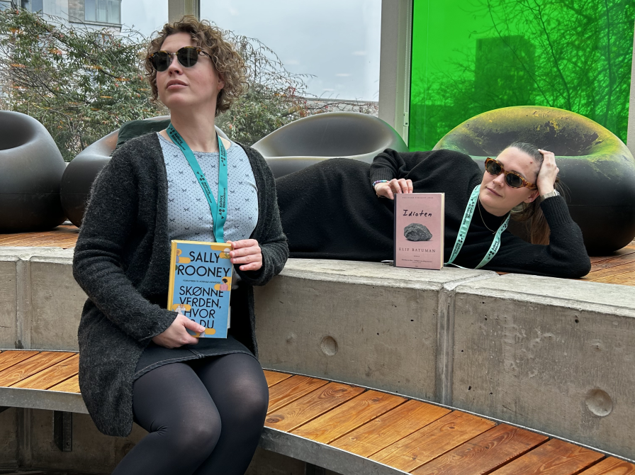 Ditte og Mie sidder i Glashjørnet på Hovedbiblioteket med hver deres bog, som kendte Hollywoodstjerner er blevet spottet med. De har begge solbriller på og ser smarte ud. Ditte sidder på bænken, Mie ligger på reposen. 