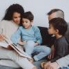 Familie sidder sammen i sofaen og læser en bog højt.