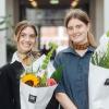 De to smilende prisvindere Helene Franch og Feline Kamber holder blomsterbuketter foran rækker af stole.
